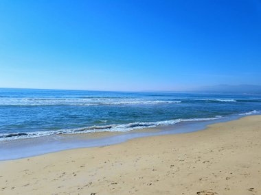 Deniz dalgaları ve kumlu sahil.