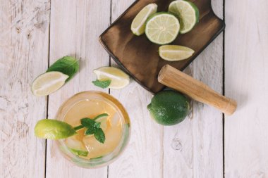 Ortadan ikiye bölünmüş bir limonu ve nane yapraklarının yanındaki tahta bir tahtanın üzerine konmuş limonu kapat..