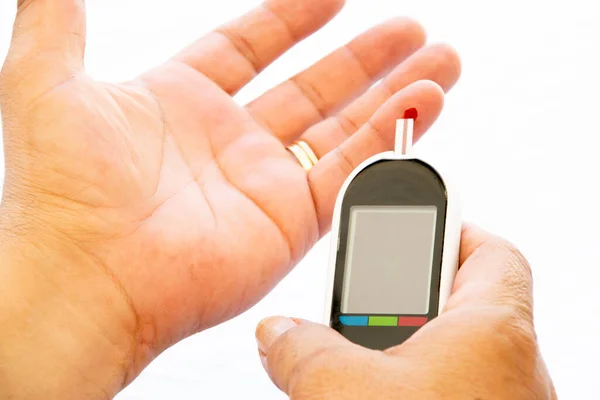 在白色背景的糖尿病装置上用一滴血做血糖测试的人 — 图库照片