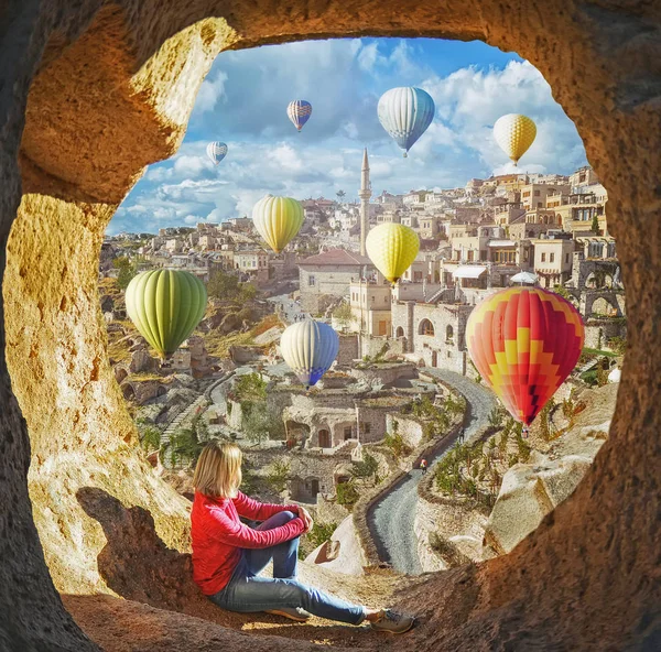 Vrouw kijken zoals kleurrijke hete lucht ballonnen vliegen over de vallei in Cappadocië — Stockfoto