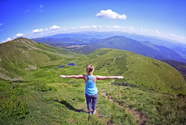 在山上举起双手的石头上的年轻女子 绿色冷杉树和蓝色湖反对在夏天的大山的背景 顶部视图 Dragobrat 乌克兰 — 图库照片