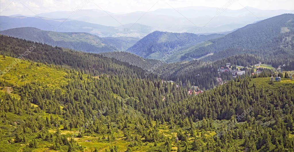 Green fir trees and houses of the village against the background of the Carpathian mountains in the summer. Dragobrat, Ukraine. Travel adventure and hiking activity  lifestyle on family summer vacation