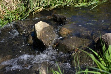 Whitecaps tarafından çevrili açık, akan dere taşları