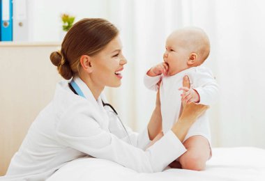 Küçük bebek kız sağlık kontrolünden yapıyor kadın çocuk doktoru gülümseyen.