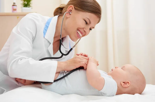 Smiling and gentle nurse examining baby girl in the room. Childcare concept.