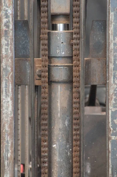 Detail of an old carpenter\'s tool, with a plunger and chain, detail of a carpenter\'s working machine, made of metal