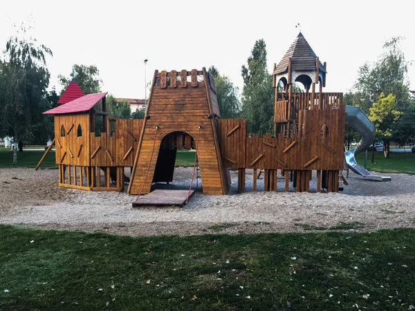 公共の公園で子供のための木製の遊び場 朝の日光は緑の木々 に囲まれています 木製の滑り台と城 — ストック写真