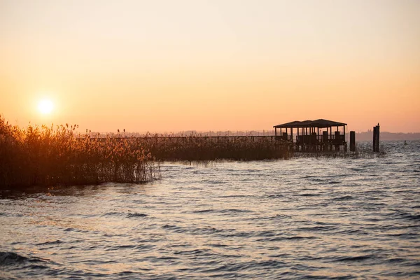 放棄された湖の桟橋に沈む夕日 パノラマ 葦で水の上の湖への木製の構造 地平線上の太陽橋の夕日とシルエット カラフルな空 夕方の雲 — ストック写真