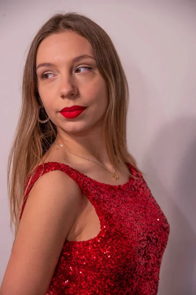 美しい深刻な若いブロンドの女性の半身像 官能的な表情でスタジオでポーズをとる女の子 完璧なメイクと スパンコールのついたドレス赤赤い唇 白い壁の背景 — ストック写真