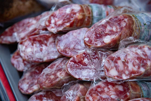 Packaged salami for sale on a market counter. Food of packaged cured meats.