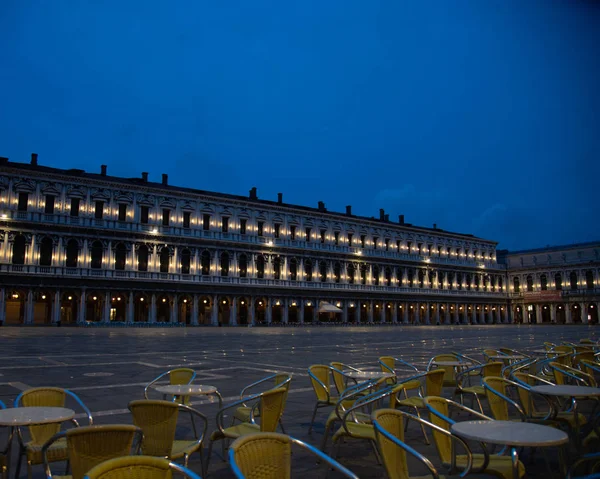 Photo at sunrise of the old Procuratie seen from the Florian cafe in Piazza San Marco in Venice, Italy. The lights of the portico building of 50 arches, which correspond to the 100 windows of the two upper floors.