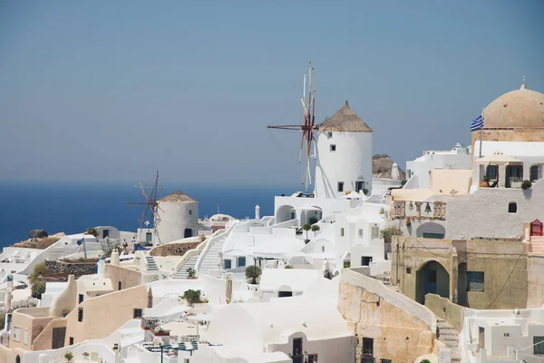 Panorama with characteristic white houses of Oia in Santorini volcanic island of the Aegean Sea in Greece. Gulf of the caldera with hotels with swimming pools, mills turned into restaurants and Greek churches.