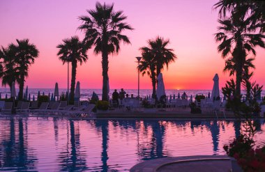 Baskı, Arnavutluk. Mayıs 2018: insanlar doğal günbatımı yerel Resort havuz ve palmiye ağaçları ile fotoğraf çekimi.