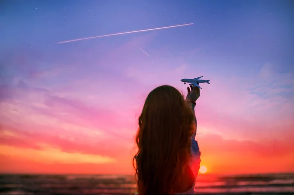 Sylwetka dziewczyna trzyma model samolotu w ręku tle scenic zachód słońca niebo. pojęcie transportu lotniczego. — Zdjęcie stockowe