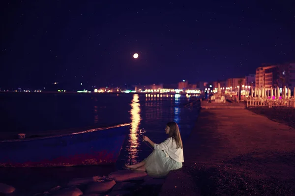 Kobieta siedzi na plaży w noc pełni księżyca, podnoszenie przy lampce wina. Durres, Albania — Zdjęcie stockowe