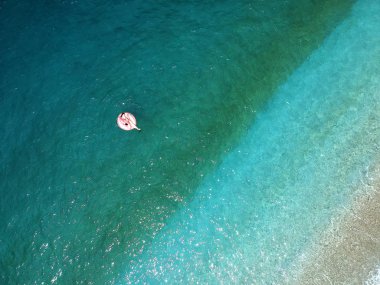 Ionian Sea Arnavutluk turquois suda dev şişirilmiş flamingo kayan nokta üzerinde genç kadın havadan görünümü