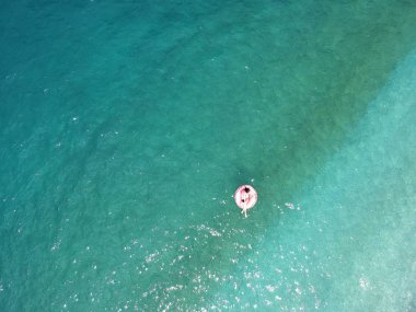Ionian Sea Arnavutluk turquois suda dev şişirilmiş flamingo kayan nokta üzerinde genç kadın havadan görünümü