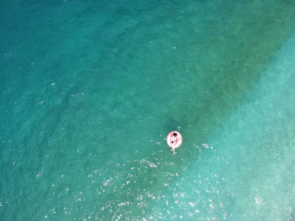 Ionian Sea Arnavutluk turquois suda dev şişirilmiş flamingo kayan nokta üzerinde genç kadın havadan görünümü