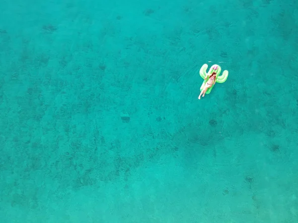 Вид с воздуха молодая женщина на гигантский надутый Кактус плавает в бирюзовой воде Ионического моря Албании — стоковое фото