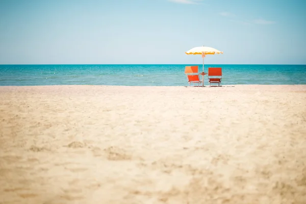 Два стула и зонтик на пляже — стоковое фото
