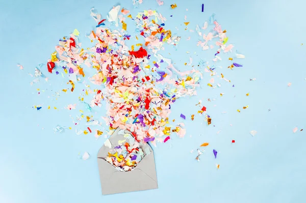 Envelop met partij confetti explosie op pastel blauwe achtergrond. — Stockfoto