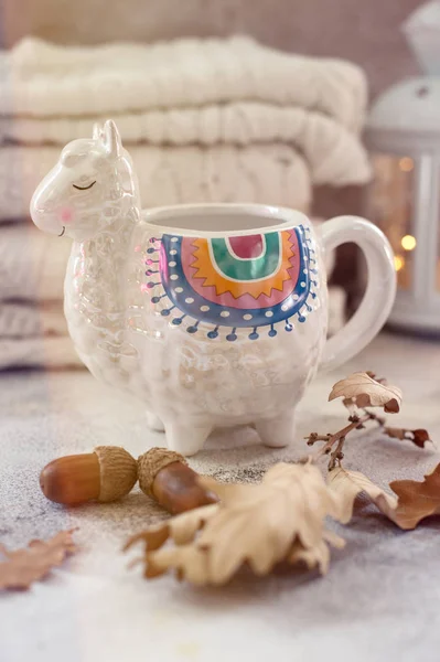 Cup of tea in trendy llama shape mug autumn leaves