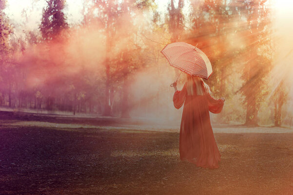 Attractive woman with a colorful smoke grenade bomb fashion running outdoors with umbrella in sunlight rays