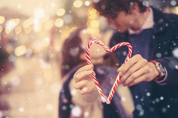 Ρομαντικό ζευγάρι κατέχει μια διακοπές Χριστούγεννα καραμέλα από ζαχαροκάλαμο καρδιά — Φωτογραφία Αρχείου