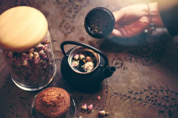 Roos thee en bloem in de pot met muffin en bokeh — Stockfoto