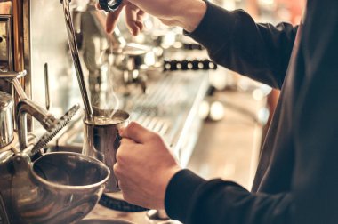 Barista, arka planda buharlı klasik bir İtalyan kahve makinesiyle espresso yapıyor.