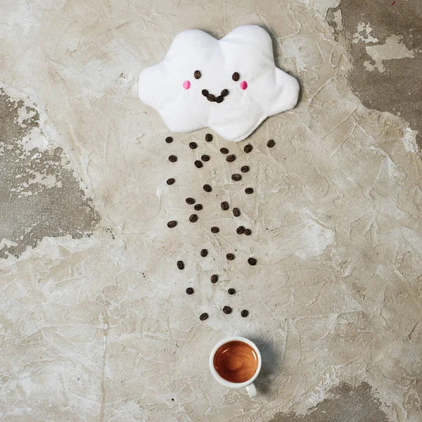 Witte wolk met blij gezicht gieten van regen van geroosterde bonen in kopje espresso. — Stockfoto