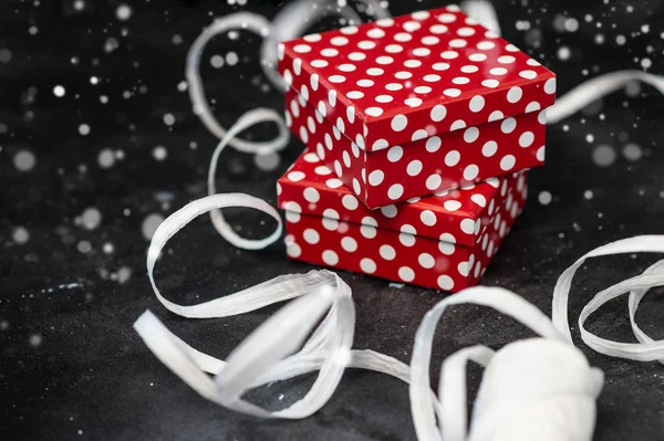 Κουτί δώρου με πουά και λευκή κορδέλα σε μαύρη επιφάνεια. — Φωτογραφία Αρχείου