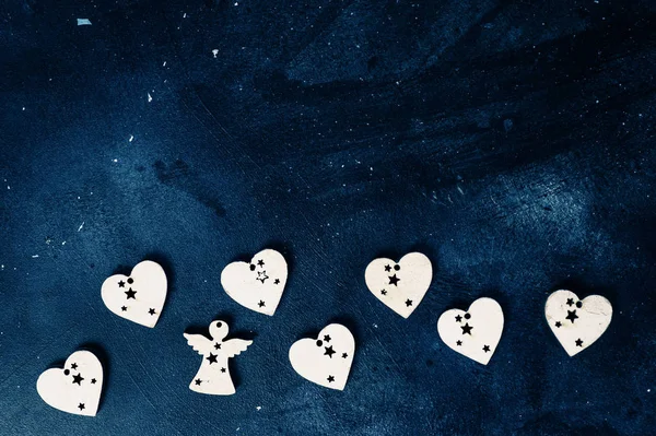 Темный граненый фон с белыми деревянными сердцами — стоковое фото