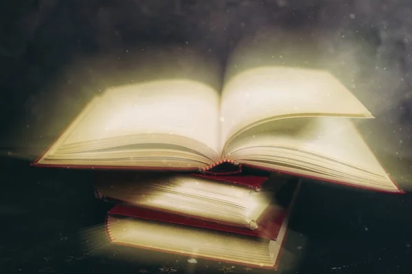 Открытая книга на деревянном винтажном столе с мистической магией яркого света на заднем плане . — стоковое фото