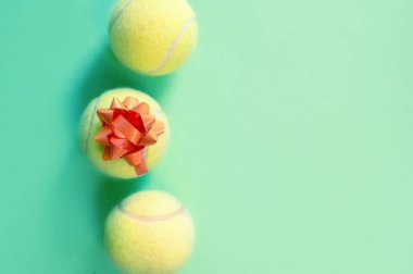 Yeşil arka planda hediye paketleme ile üç tenis topları.
