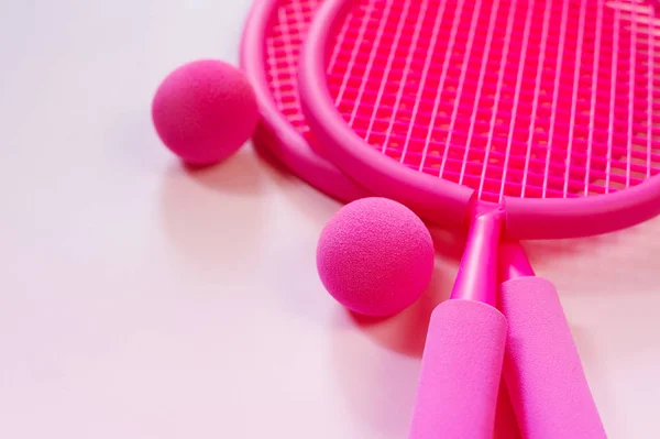 Two fuchsia pink beach tennis rackets and ball