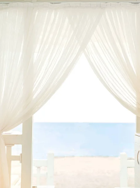 Вид на пляж и море за белыми шторами — стоковое фото