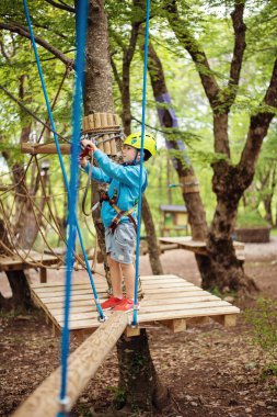 Ağaçların arasından geçen genç çocuk, macera parkında ekstrem spor