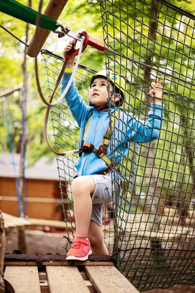 Giovane ragazzo che passa via cavo tra gli alberi, sport estremo nel parco avventura — Foto Stock