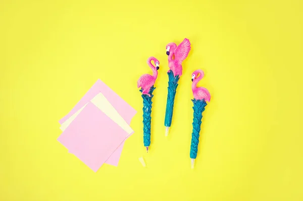 Desktop flatlay: caneta com flamingo e papel rosa deitado fundo amarelo vibrante — Fotografia de Stock