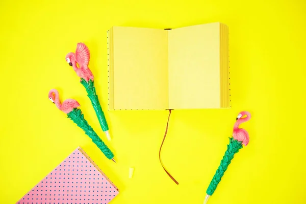 Bureaublad flatlay: pen met Flamingo en roze papier liggend levendige gele achtergrond — Stockfoto