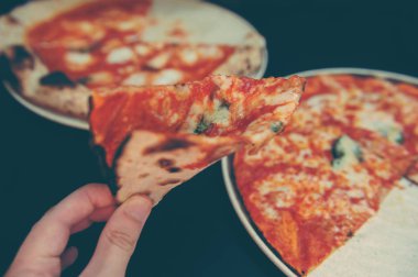 Tanınmayan halkların yüksek açı çekimi bir dilim pizzayı avuçlayarak