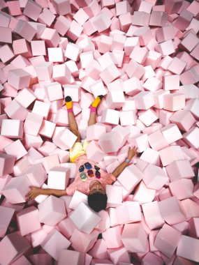 Bir oyun odasında yumuşak renkli küpler üzerinde yatan mutlu çocuk