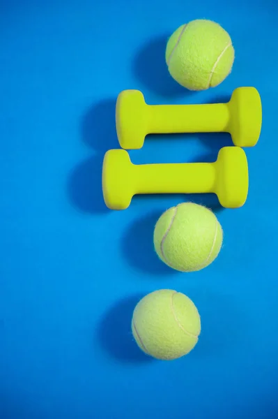 トレーニングコンセプトフィットネス背景ダンベル青い背景にテニスボール — ストック写真