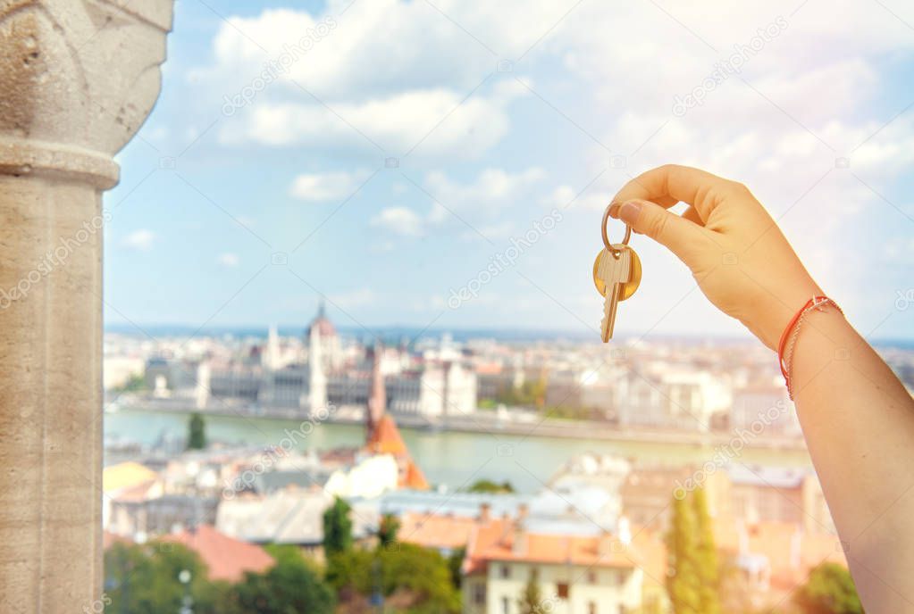 Real estate agent with house keys and European cityscape