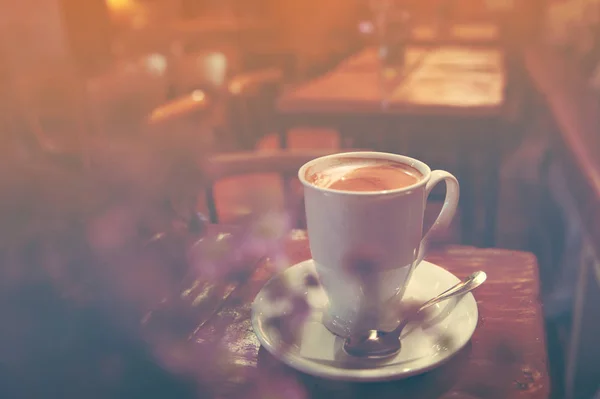 Tutup cangkir kopi latte putih di meja dekat jendela dengan pijar matahari — Stok Foto