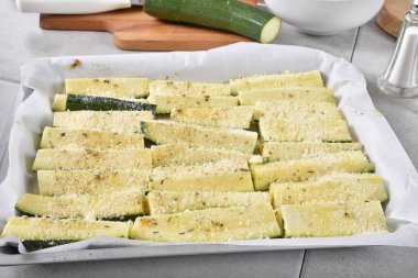 Fırın için hazır bir pişirme tavada zeytin yağı, garlick ve parmesan peyniri ile terbiyeli kabak dilimleri