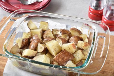 Bir cam pişirme çanağı içinde baharatlar kavrulmuş patates yüksek açılı görünüş.