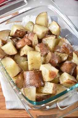 Delicious çeşnilikler ile cam güveç çanağı altın kahverengi pişmiş patates kuşbaşı.