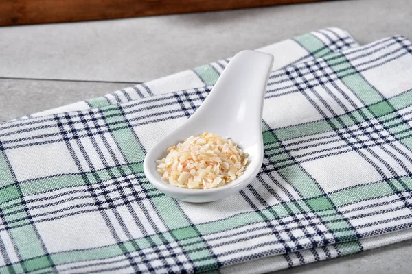 A ceramic spoon full of organic dried minced onions.